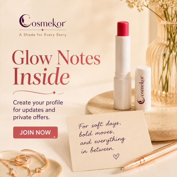 Cosmekor Glow Notes lipstick in a white tube with a pink cap, shown beside its cap and a handwritten note on a beige tabletop with jewelry and a pen.